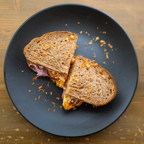 A toasted sandwich, cut in half on a dark plate